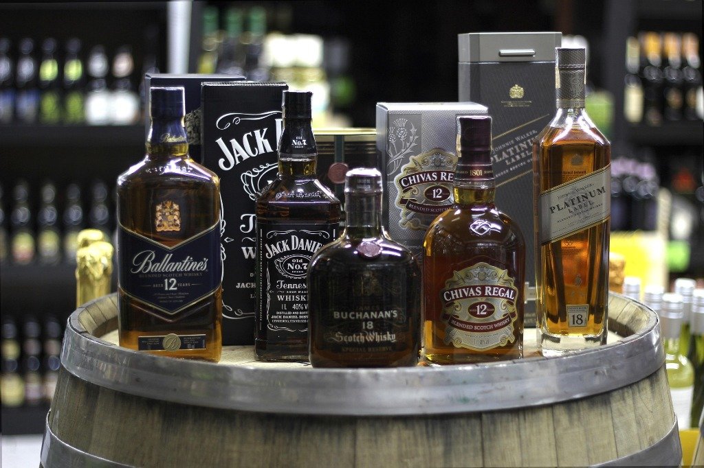 Selection of whisky bottles on an oak aging barrel at Madhuloka