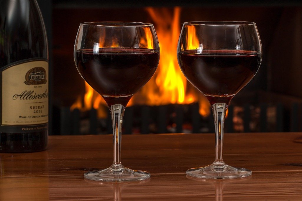 Two glasses of red wine by a cozy warm fireplace at Madhuloka